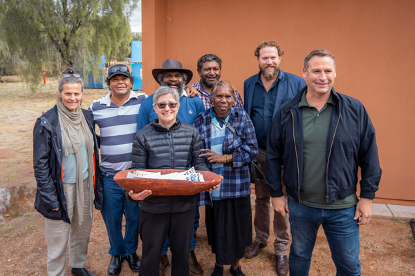 Eight forum attendees holding a coolamon, carrying vessel, presented to Carol and her colleagues at the ‘working together for better water in the bush’ forum.