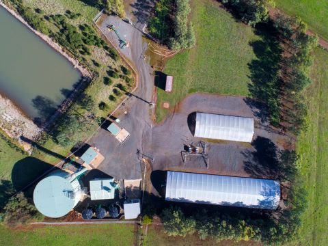 Aerial view of the Forest Hill Water Treatment Plant which shows a large body of water and multiple buildings surrounded by green grassland.