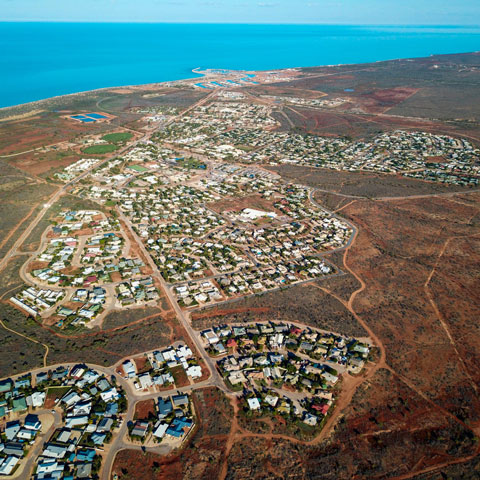Township of Exmouth in foreground with vibrant blue ocean behind.