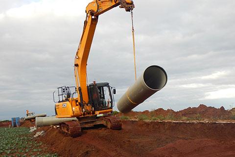 Crane placing pipeline into ditch