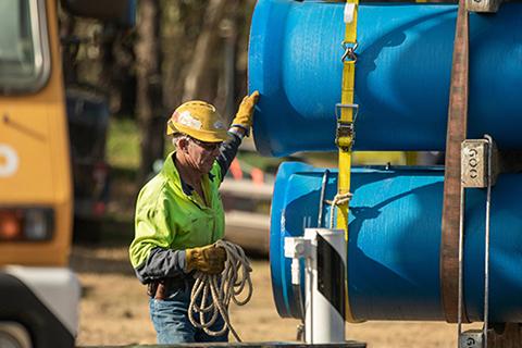 Man in hardhat and hi-vis vest checks pipelines before installation.