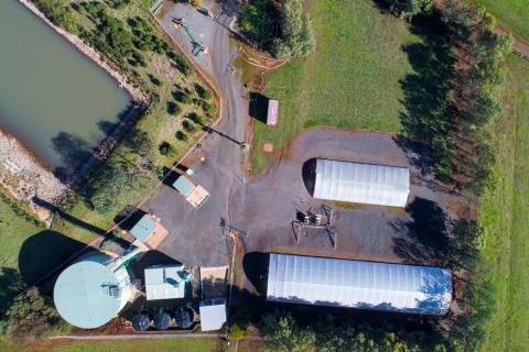 Aerial view of the Forest Hill Water Treatment Plant which shows a large body of water and multiple buildings surrounded by green grassland.