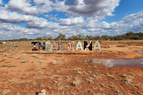 Photograph of an arid outback landscape with a multi-coloured Indulkana sign. 