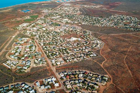 Township of Exmouth in foreground with vibrant blue ocean behind.
