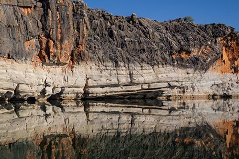 Gorge in Fitzroy Crossing in Western Australia with layered cliff in the background and water in the foreground.