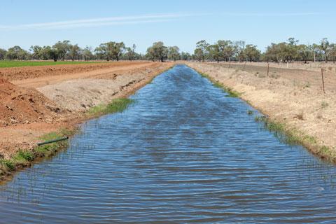 Channel of water running through a dirt paddock.